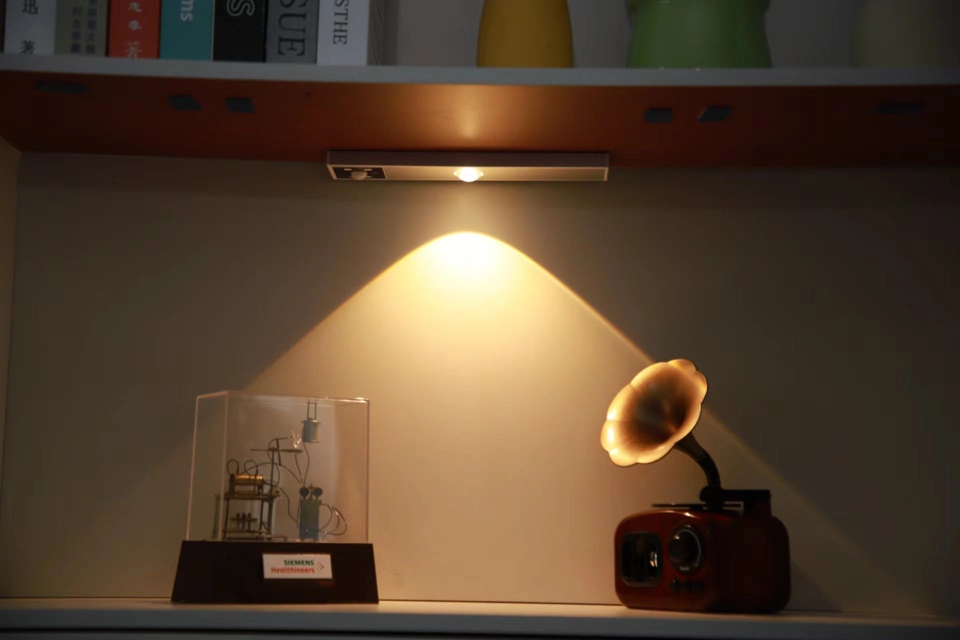 Retro metallic desk lamp with adjustable design, featuring a 20cm gray shade and a single LED bulb, placed on a wooden desk next to a computer and shelves in a warmly lit space.