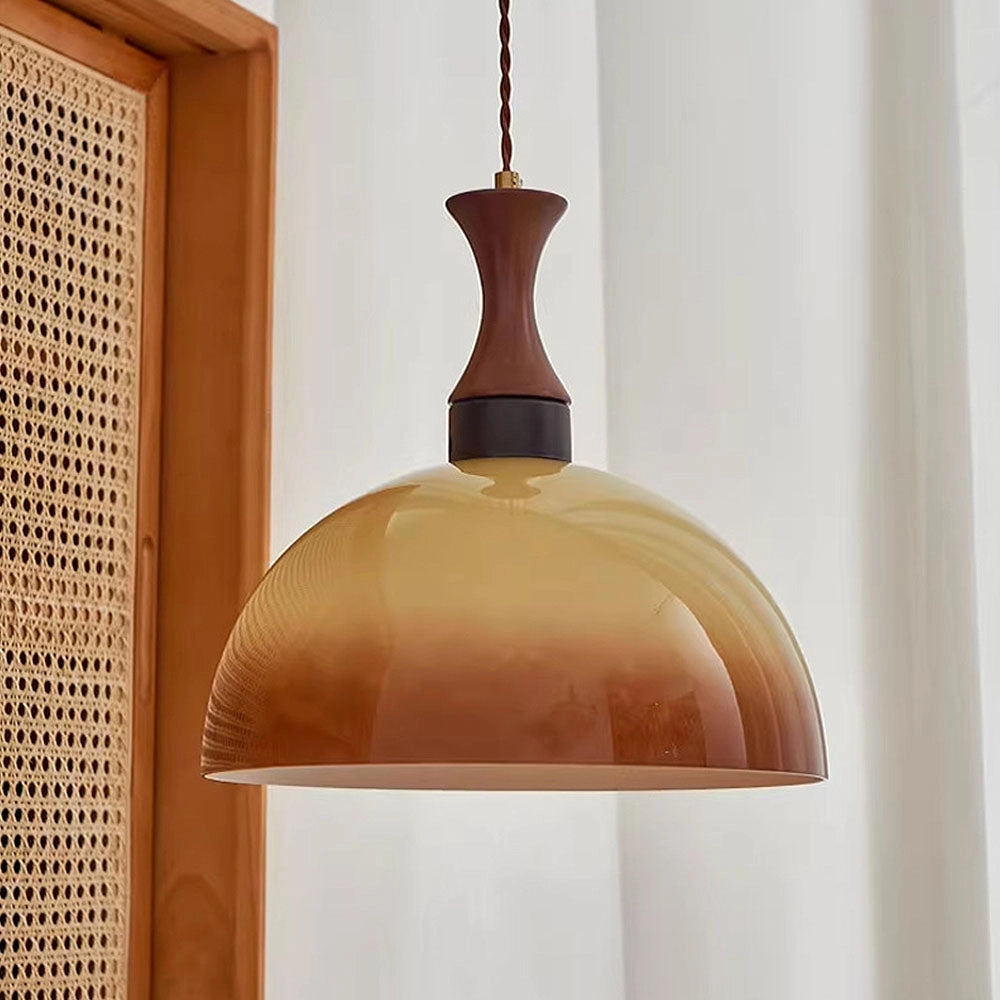 Retro yellow mid-century pendant light with a wooden accent and amber shade, hanging in a modern home interior with plants and large window in the background.