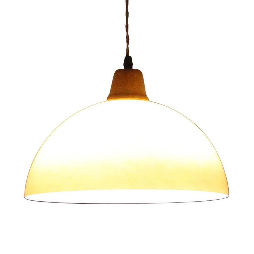 Retro yellow mid-century pendant light with amber metal dome shade, hanging from ceiling; ideal for modern home and plant decor.