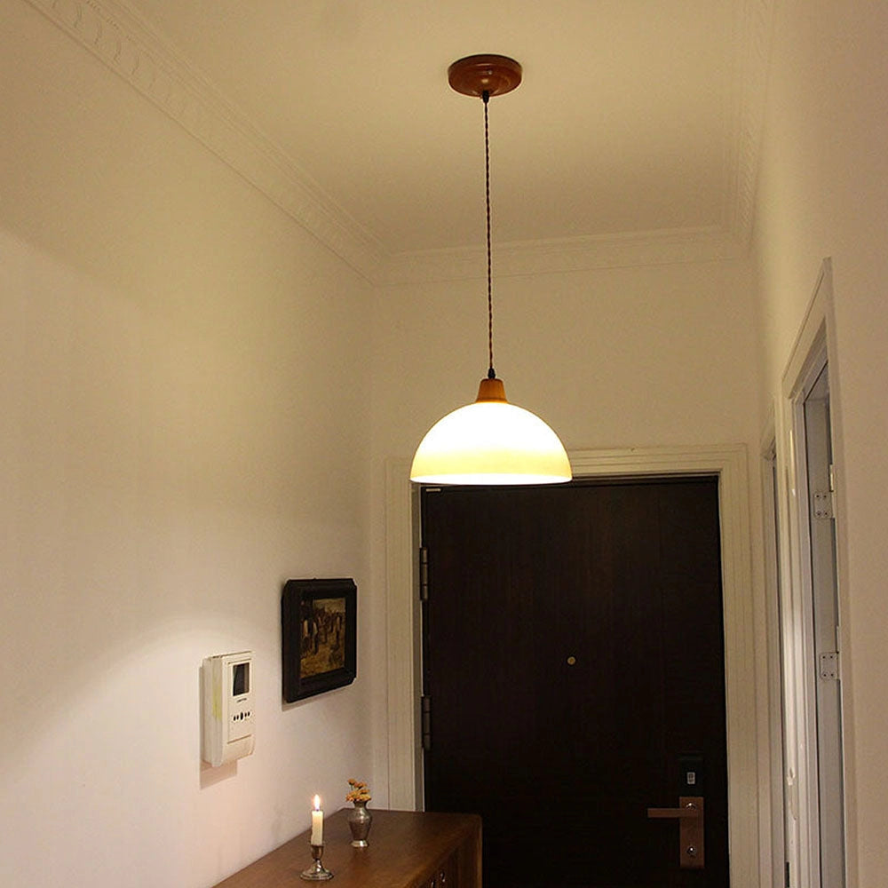 Retro yellow mid-century pendant light hanging above a wooden table in a modern home interior with plants.