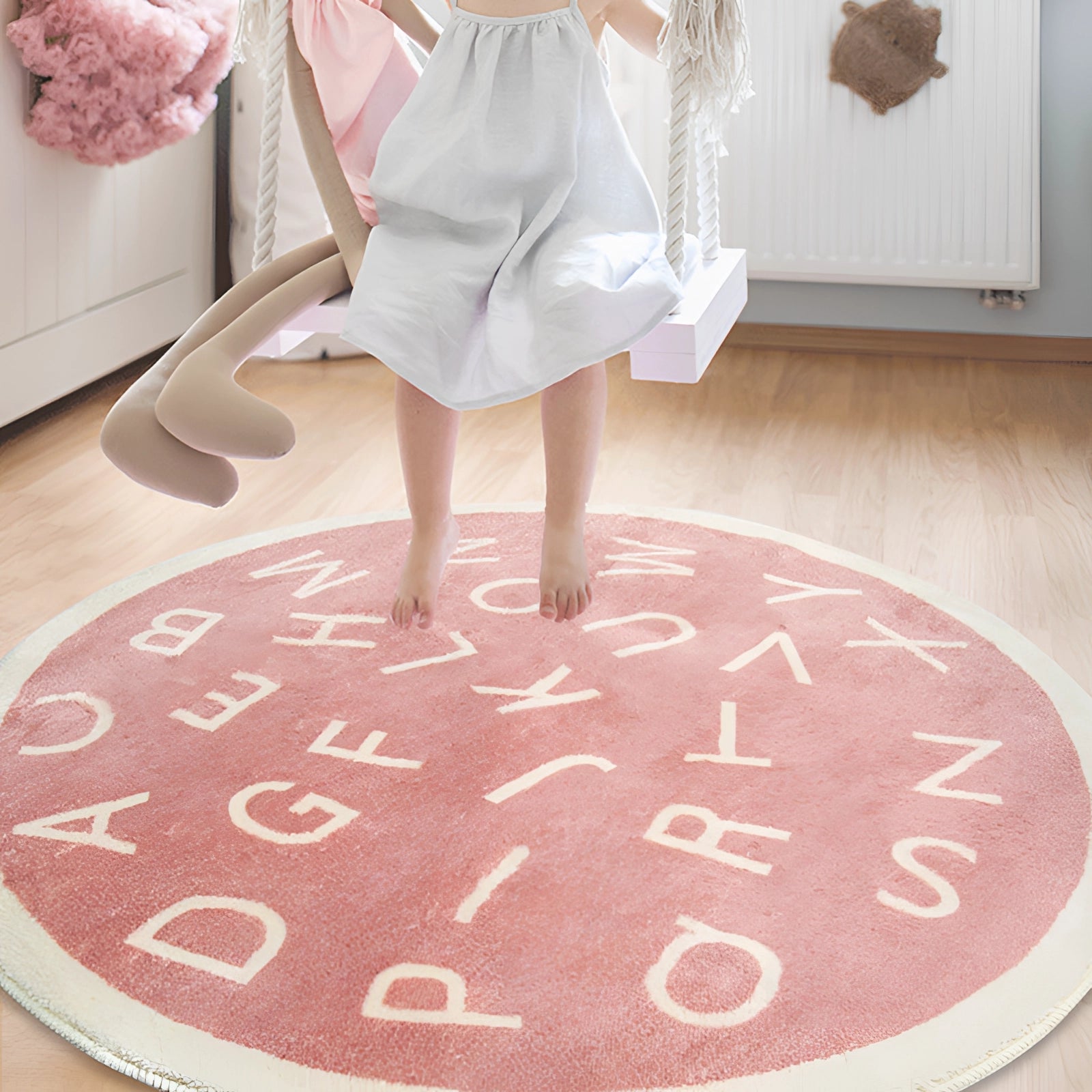 Round green alphabet rug on a wooden floor in a nursery or playroom setting, featuring a colorful educational design with letters.