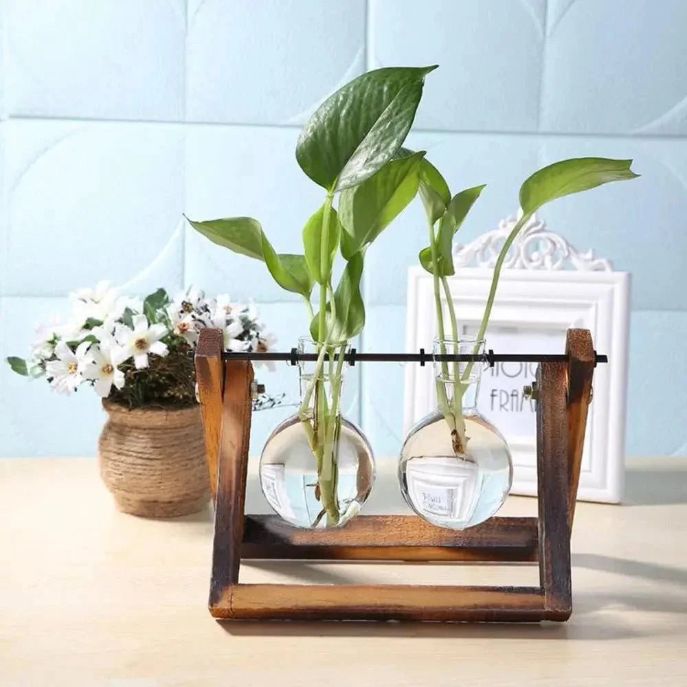 Rustic wooden vase holder in a minimalist triangular stand design, featuring a glass vase with a vibrant houseplant and delicate flowers.