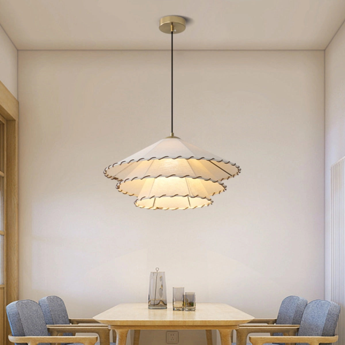 Modern tiered chandelier with gold interior, scalloped edges, and LED lighting, hanging above a wooden table and chairs in a contemporary interior design setting.