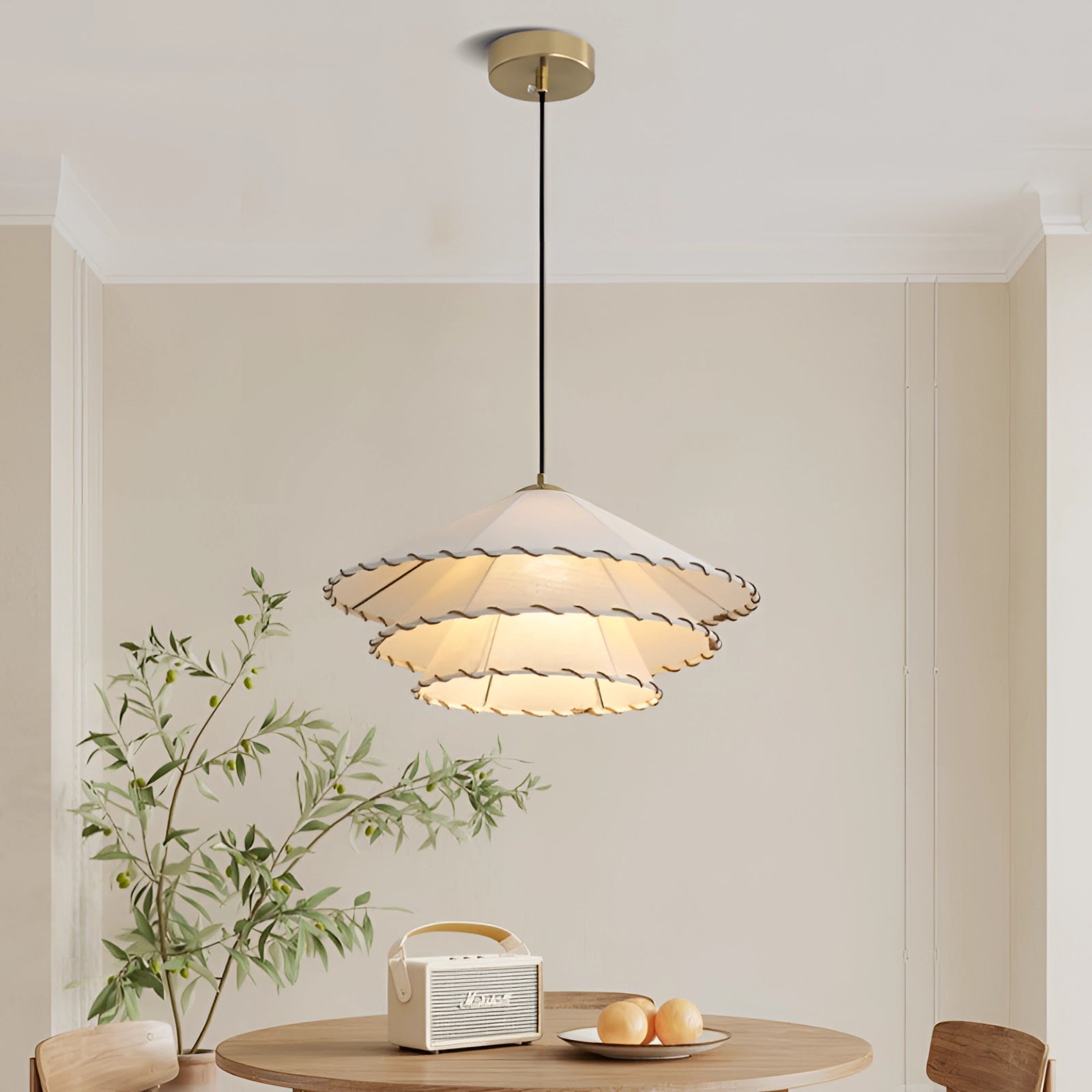 Modern tiered scalloped LED pendant light with gold interior hangs above a stylishly set table in a contemporary interior design setting, featuring natural wood elements and complementary dishware.