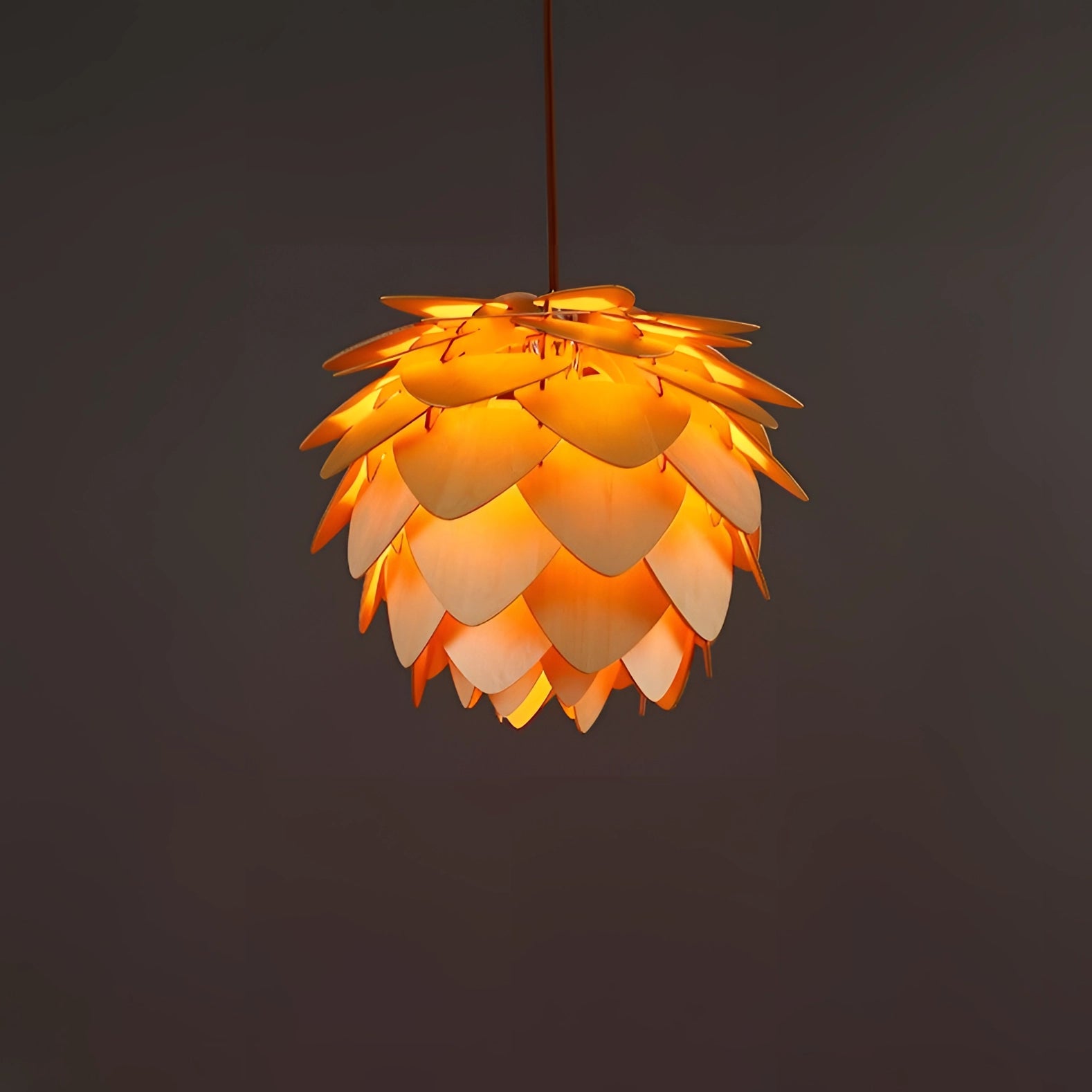 Scandinavian pinecone pendant light with a modern organic design, featuring amber-tinted lampshade with circular and triangular elements, suspended as a ceiling fixture.