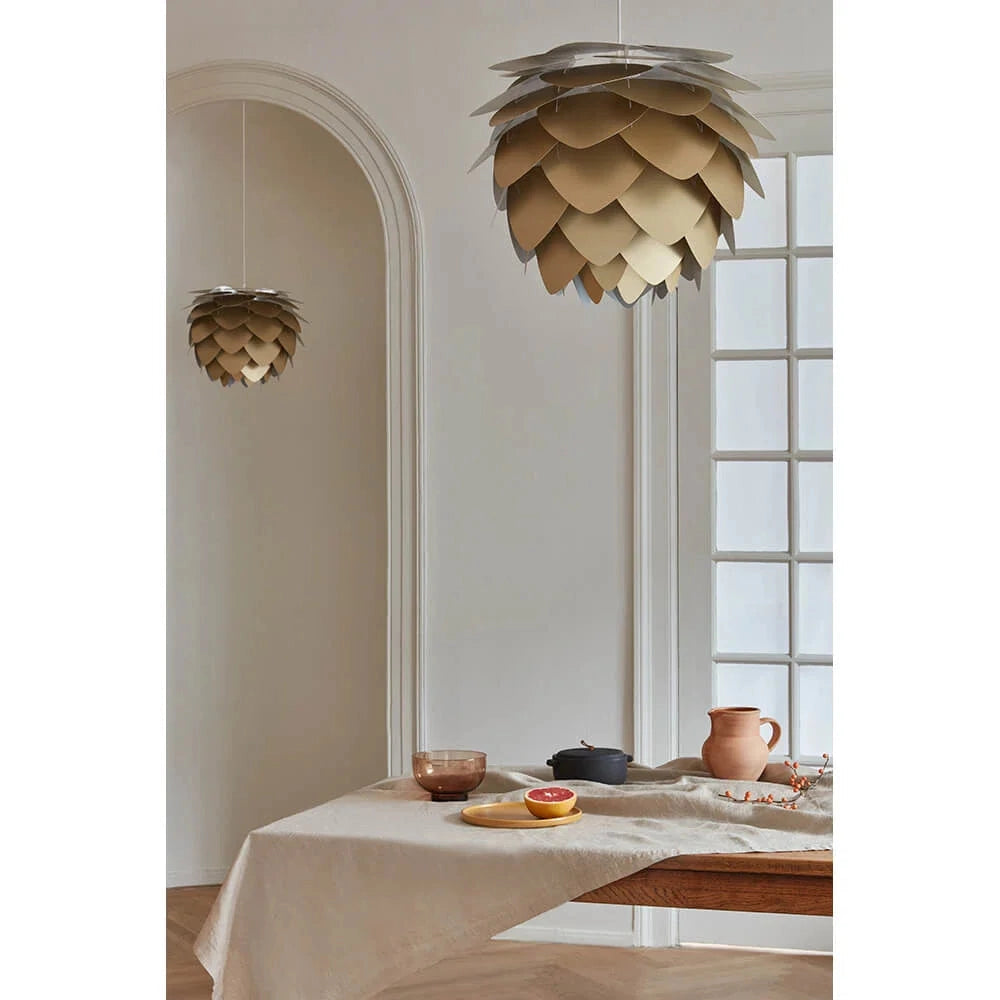 A Scandinavian Pinecone Pendant Light with a modern organic design, featuring a beige wood shade, hanging from the ceiling in an interior space with a window and table, creating a warm and comfortable ambiance.