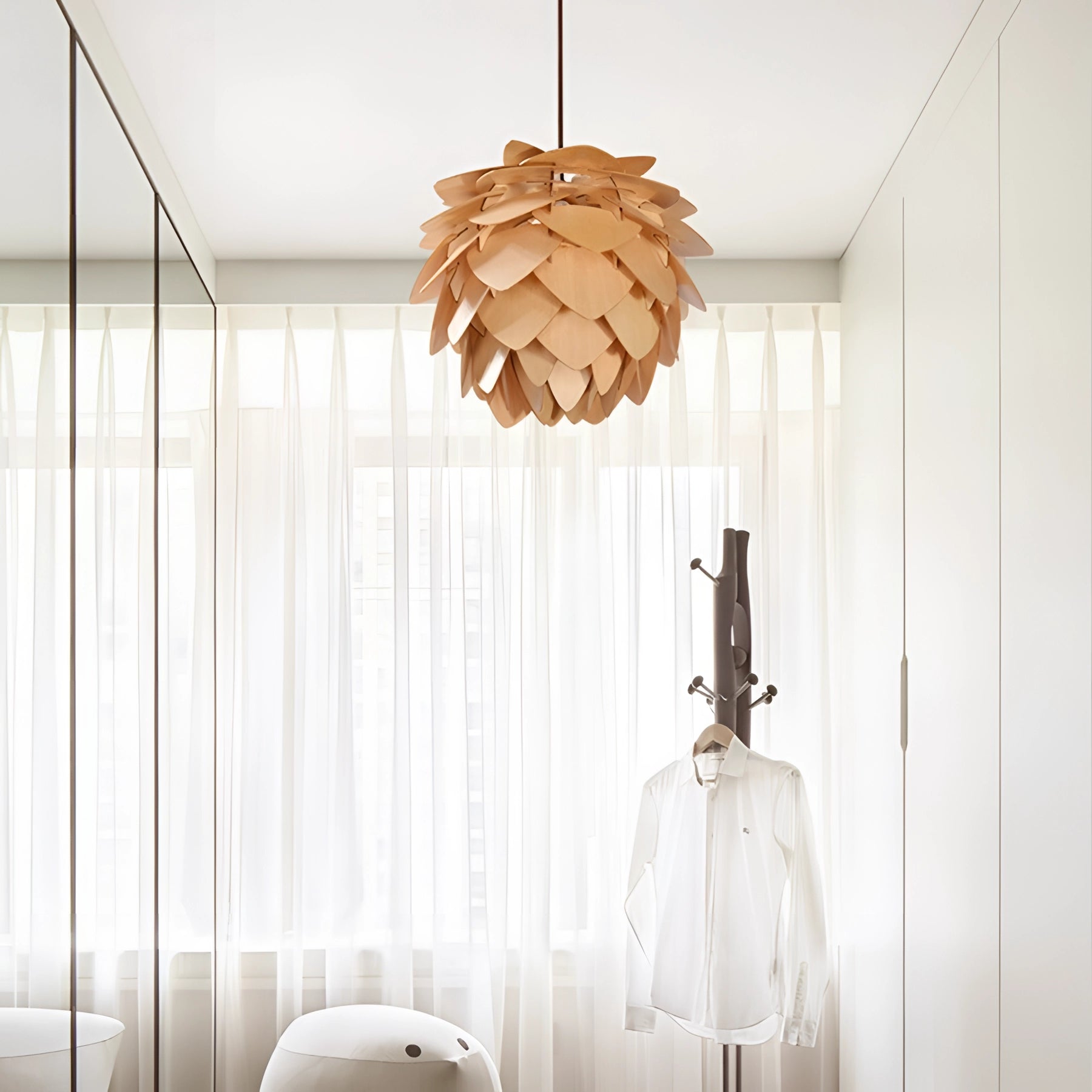 Scandinavian Pinecone Pendant Light hanging in a modern interior setting, showcasing its organic wooden design with a warm glow, positioned near a window allowing natural light to complement the lamp's illumination.