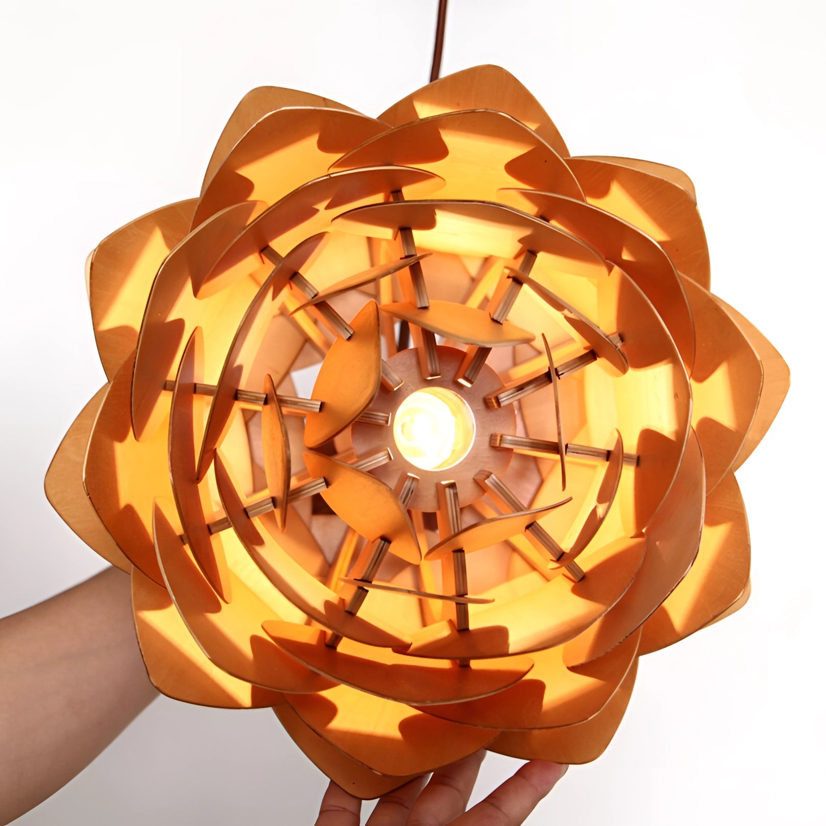 A modern Scandinavian pendant light designed to resemble a pinecone, featuring an organic pattern with amber-toned petals creating a warm and inviting glow, hanging from the ceiling with a symmetrical arrangement.