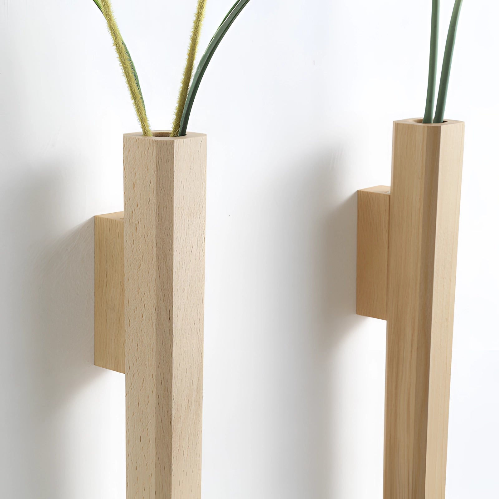 Scandinavian-style wall-mounted wooden flower vase featuring a minimalist vertical design, holding a small houseplant with green leaves, showcasing a sleek rectangular shape made from hardwood.