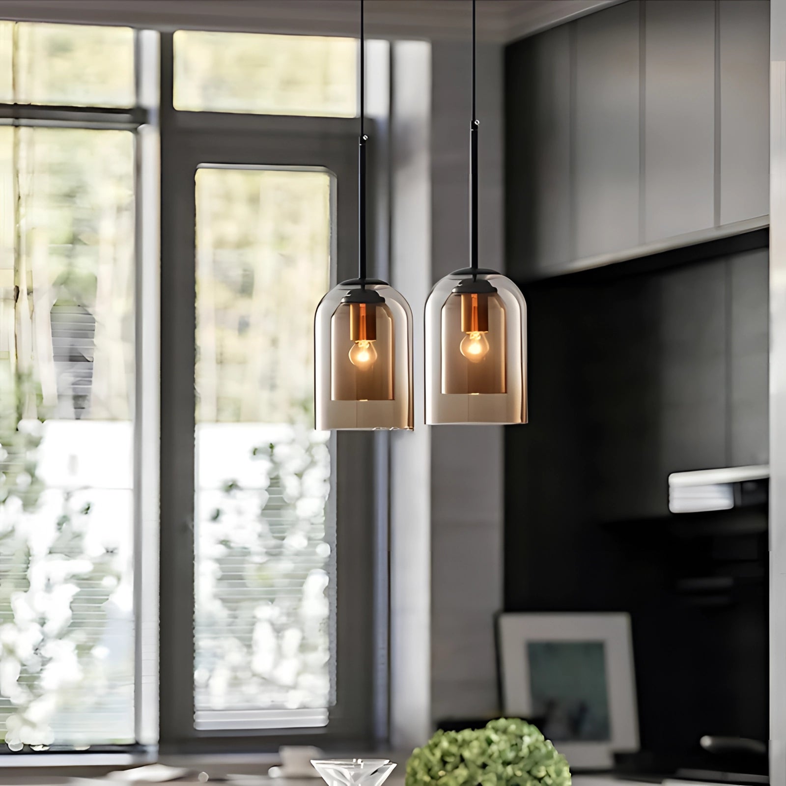 Modern smoke glass pendant light with a transparent design, featuring an Edison bulb, hanging in an interior setting with wooden elements and a window nearby.