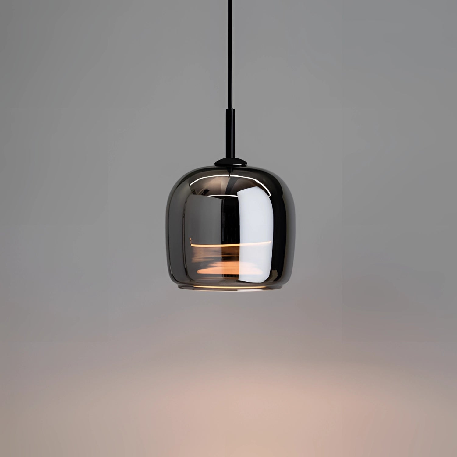 Minimalist industrial smoked glass pendant light hanging from a ceiling, illuminating a modern kitchen interior with wood and metal accents.