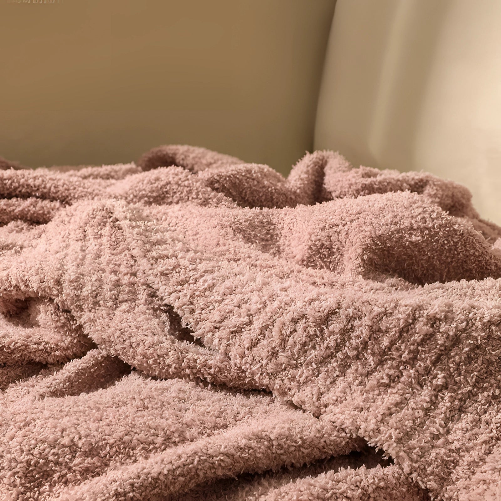 Soft pink velvet blanket draped over a plush surface, showcasing its luxurious texture and cozy design, with a subtle pattern and a touch of elegance against a warm, neutral backdrop.