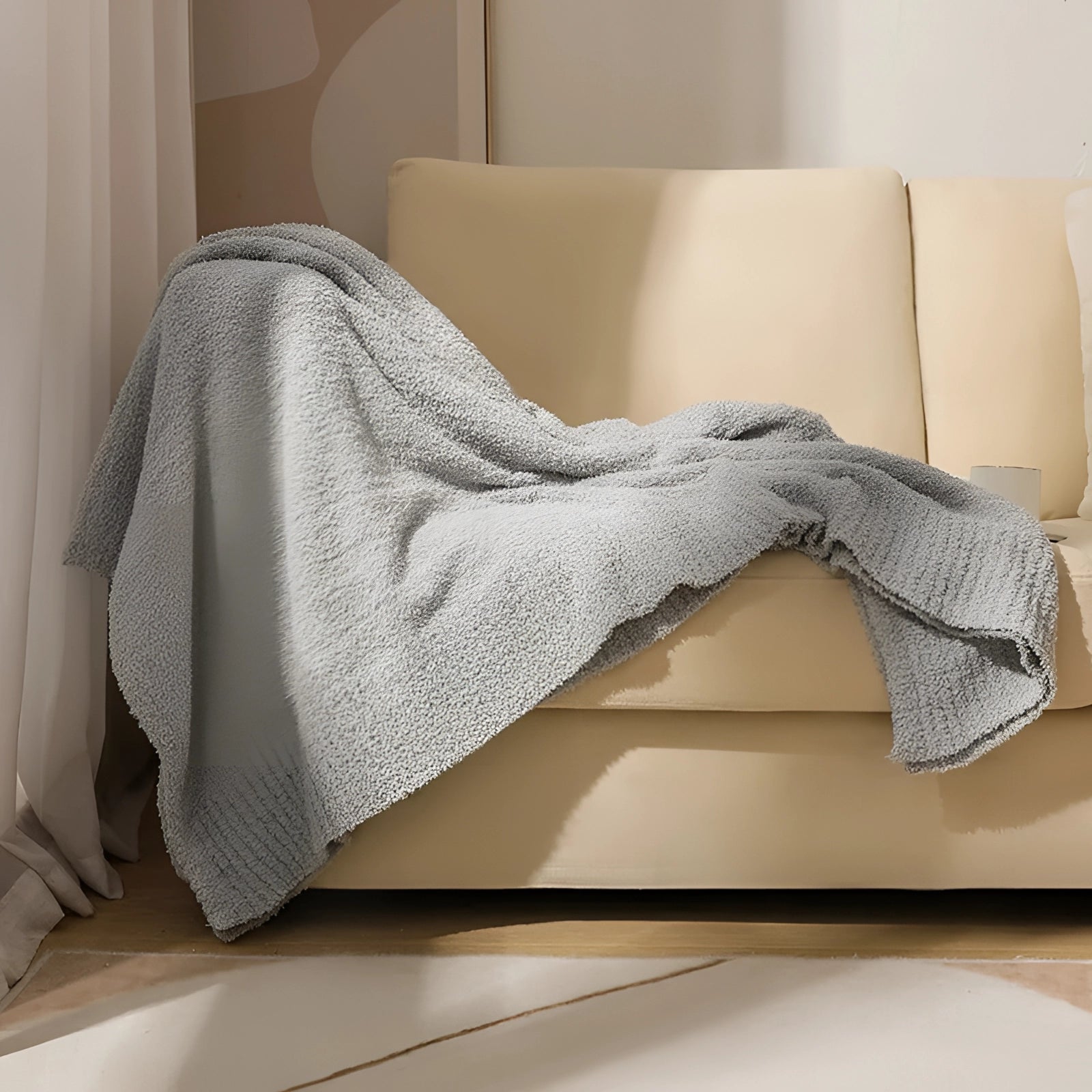 Soft plush pink velvet blanket in a gray color variant, measuring 150 x 200 cm, draped on a hardwood floor with a visible human leg, emphasizing comfort and luxury.