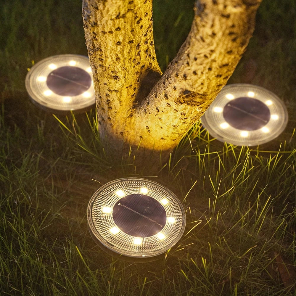 Solar LED pathway lights illuminating a garden at night, with vibrant yellow light casting over grass and wooden pathway.