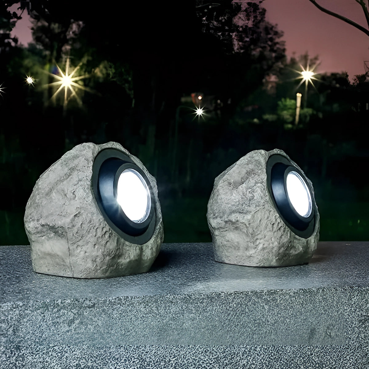 Solar-powered LED rock lights illuminating a garden at night with a natural and decorative appearance.