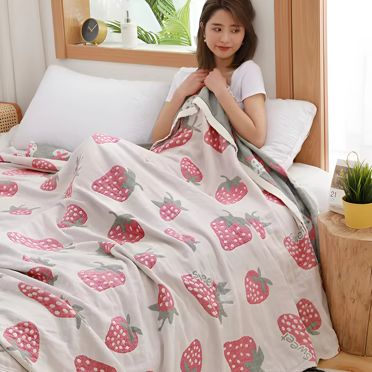 A cozy strawberry pattern blanket draped over a couch in a stylishly decorated room, featuring a white background with vibrant red strawberries, adding a touch of comfort and fashion to the interior design.