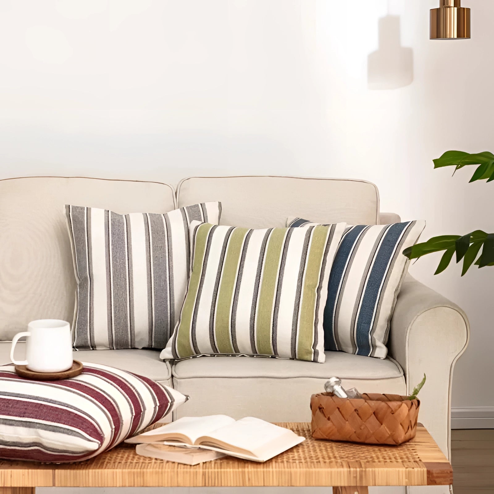 Neutral-colored striped accent pillows arranged on a modern living room couch with wooden flooring in the background.