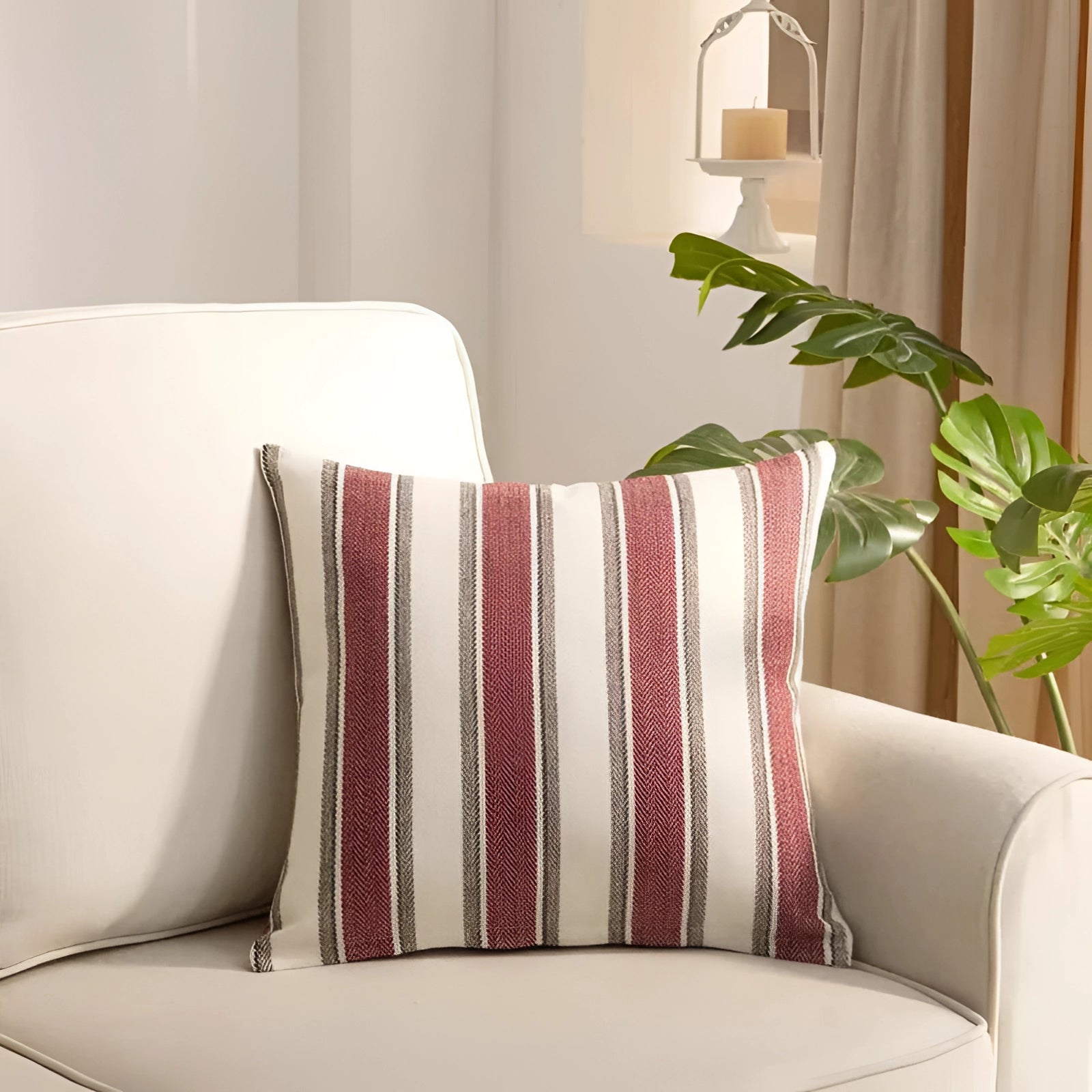 Striped red accent pillow on a modern living room couch, surrounded by neutral decor elements, including a plant and wooden furniture, with soft lighting enhancing the comfortable ambiance.