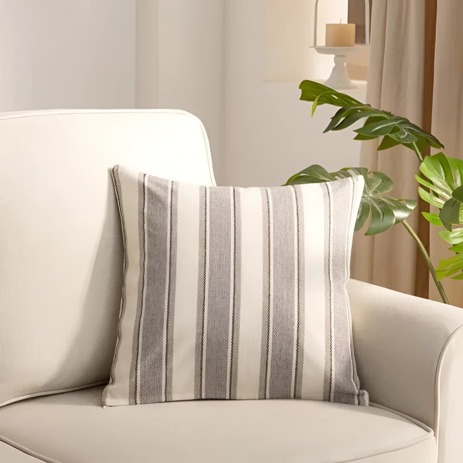 Striped gray accent pillow on a contemporary couch in a modern living room setting, featuring neutral decor elements such as a wooden coffee table, indoor plant, and a soft textile.