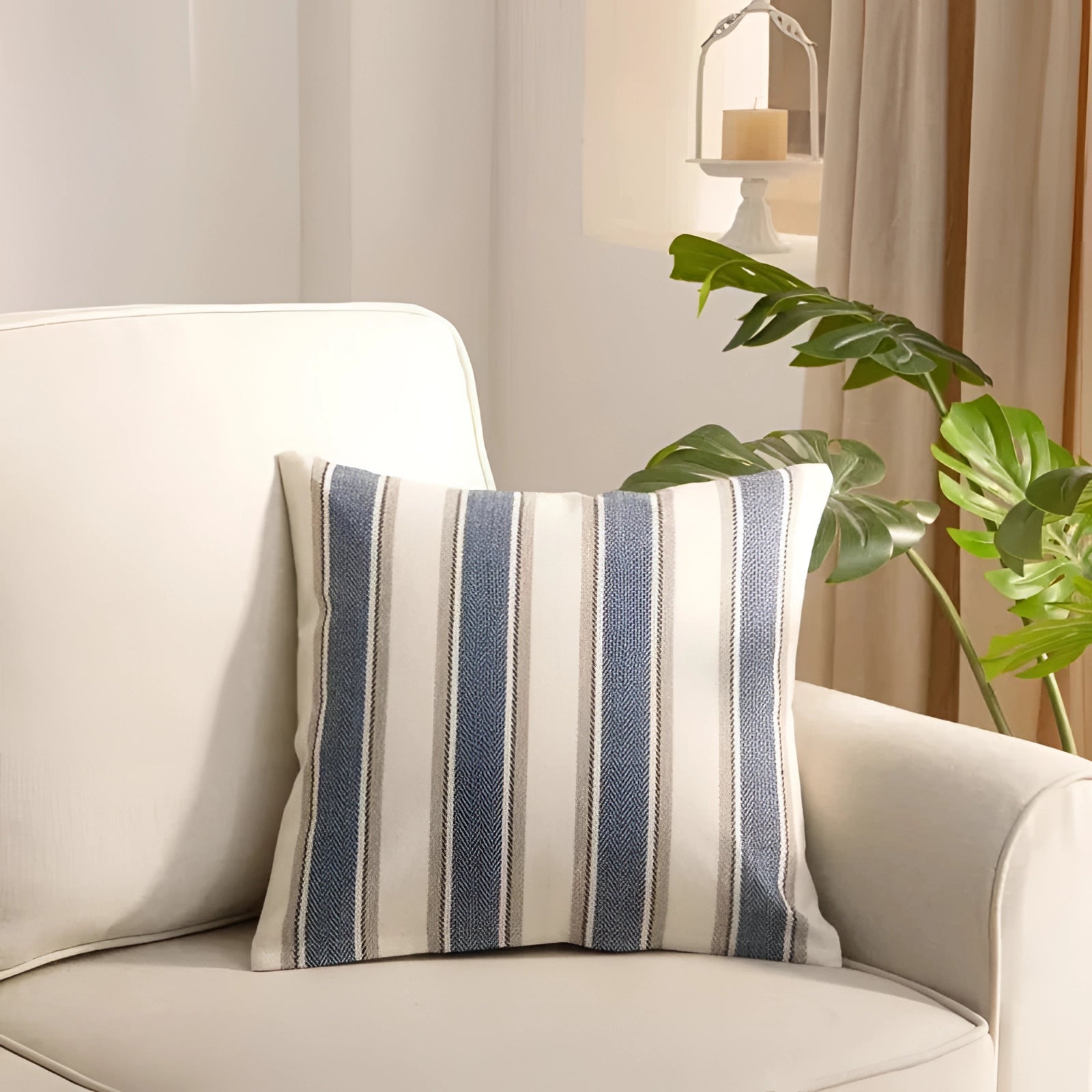 Striped blue accent pillow measuring 45 x 45 cm placed on a couch in a modern living room setting, surrounded by neutral decor elements like white furniture, lighting, and a potted plant for added comfort and style.