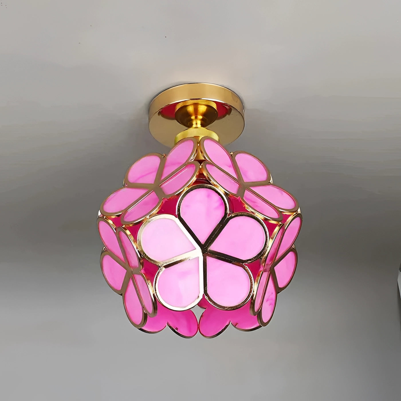 Tiffany style stained glass ceiling light with a pink Art Nouveau design, featuring petal-shaped patterns and a symmetrical circular arrangement.