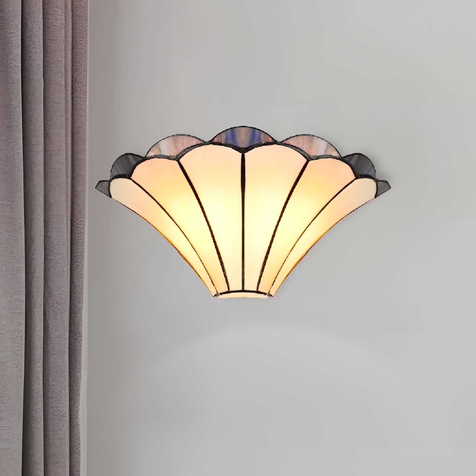 Tiffany-style stained glass shell wall sconce with an art deco design featuring beige and multicolored geometric patterns, mounted on a wooden surface.