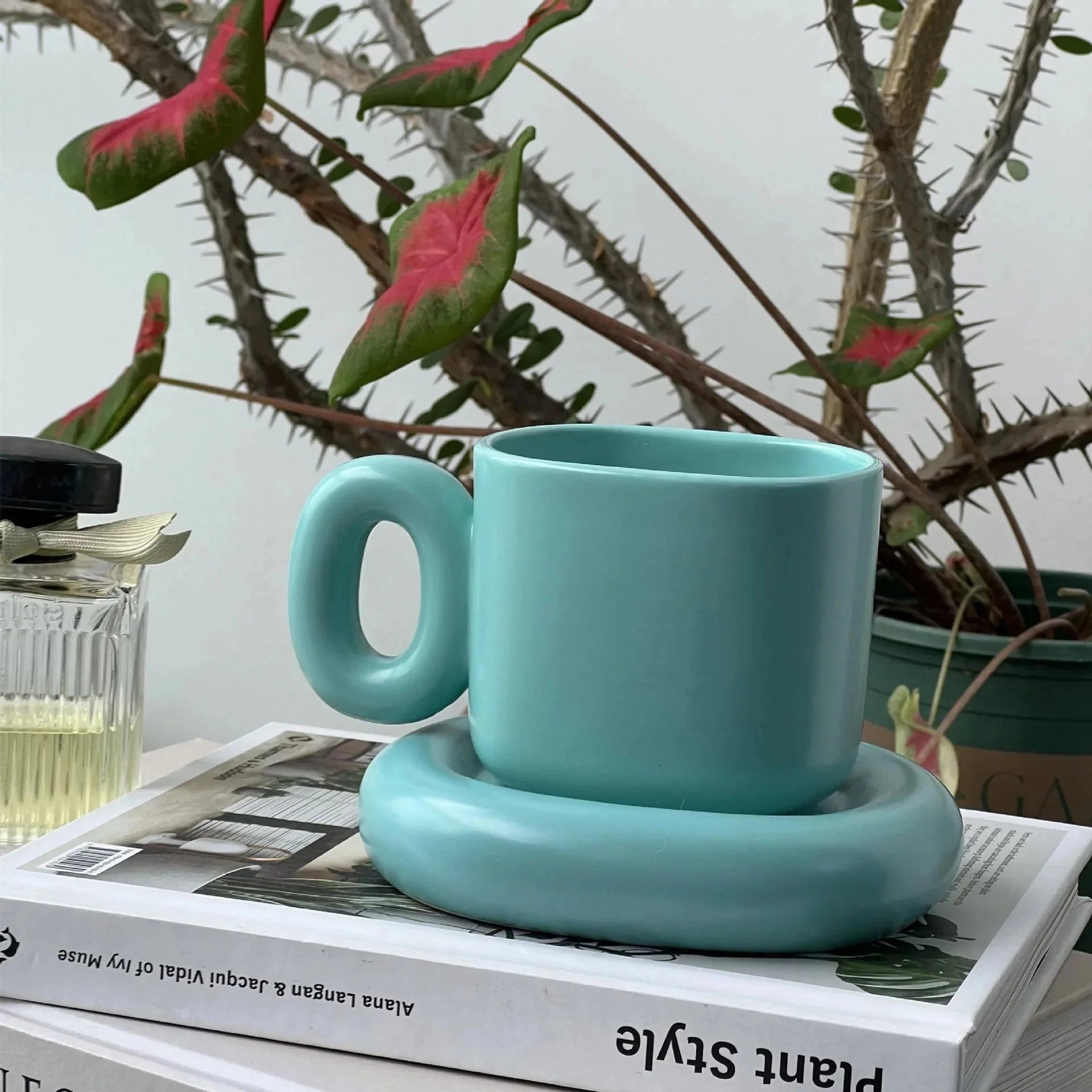 
A turquoise ceramic mug with a unique handle, designed as a modern coffee cup. The mug has a smooth finish and a capacity of 280ml, perfect for serving coffee or tea. It features a contemporary design in a blue-green shade.