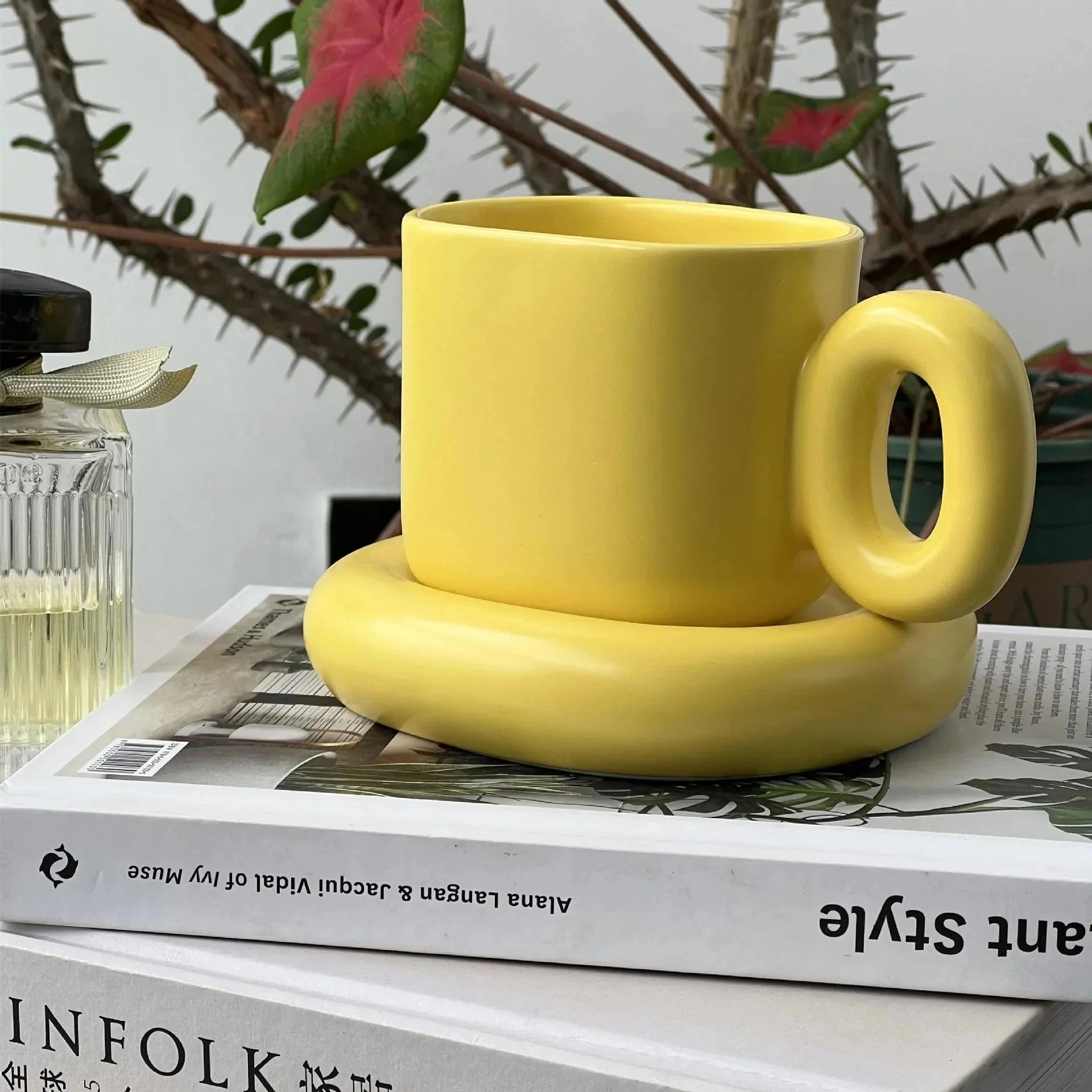 Turquoise ceramic mug with a unique handle, featuring a modern design in a vibrant yellow color, holding 280ml, set against a backdrop with a decorative plant.