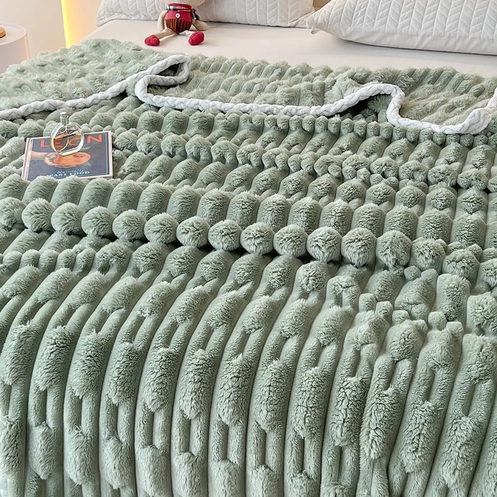 A turquoise chunky knit blanket with a plush braided texture, displayed on a grassy surface. The blanket is large, measuring 200cm x 230cm, and features a luxurious, cozy design in a green hue.