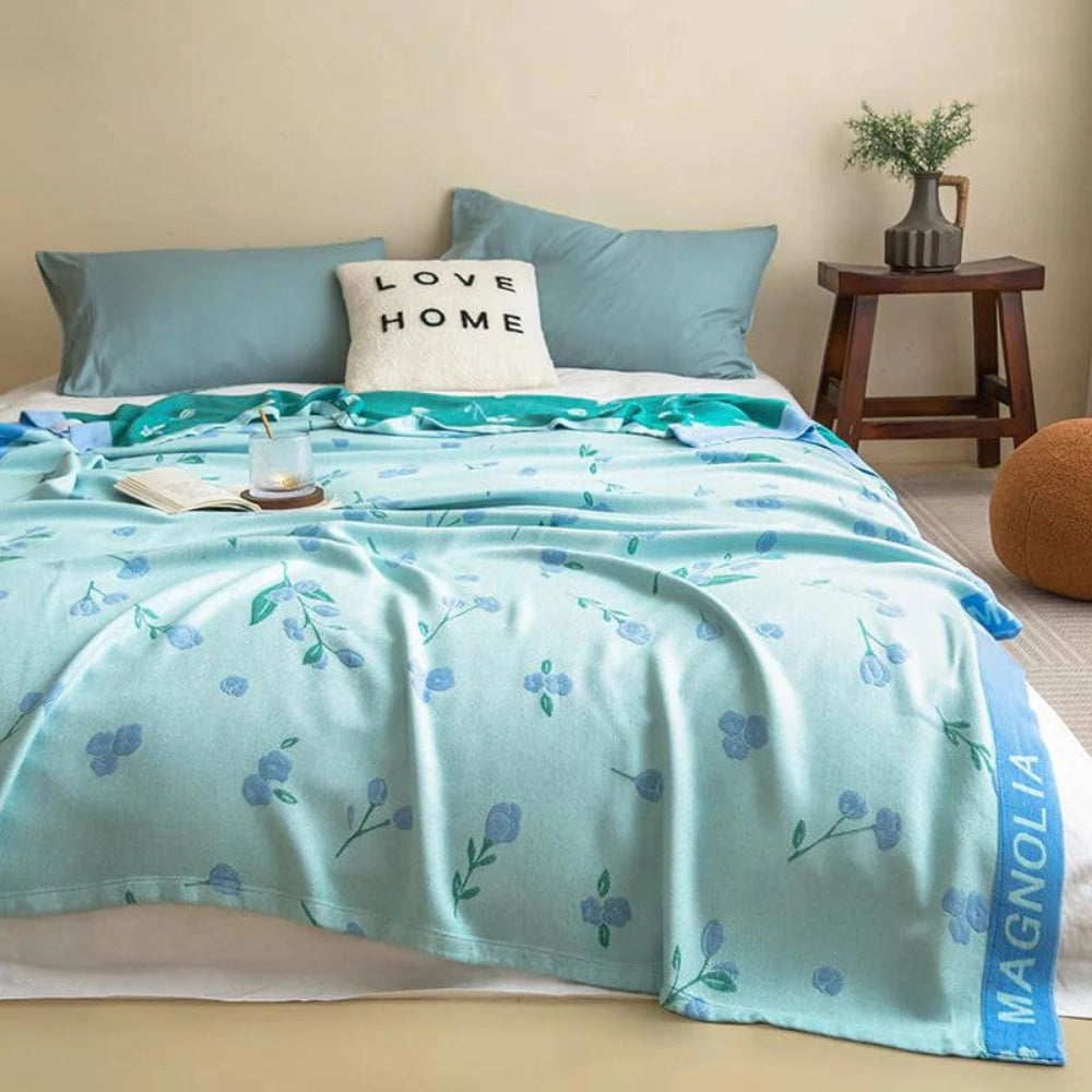 Turquoise floral designer bamboo cooling blanket in a king size, measuring 150x230cm, displayed on a bed with complementary blue and green hues in a stylish interior setting.