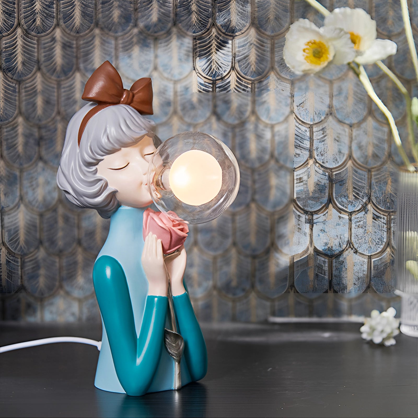 Whimsical ceramic bubble statue featuring gold bunny ears, with a playful cartoon-like design, surrounded by artistic elements such as flowers and twigs.