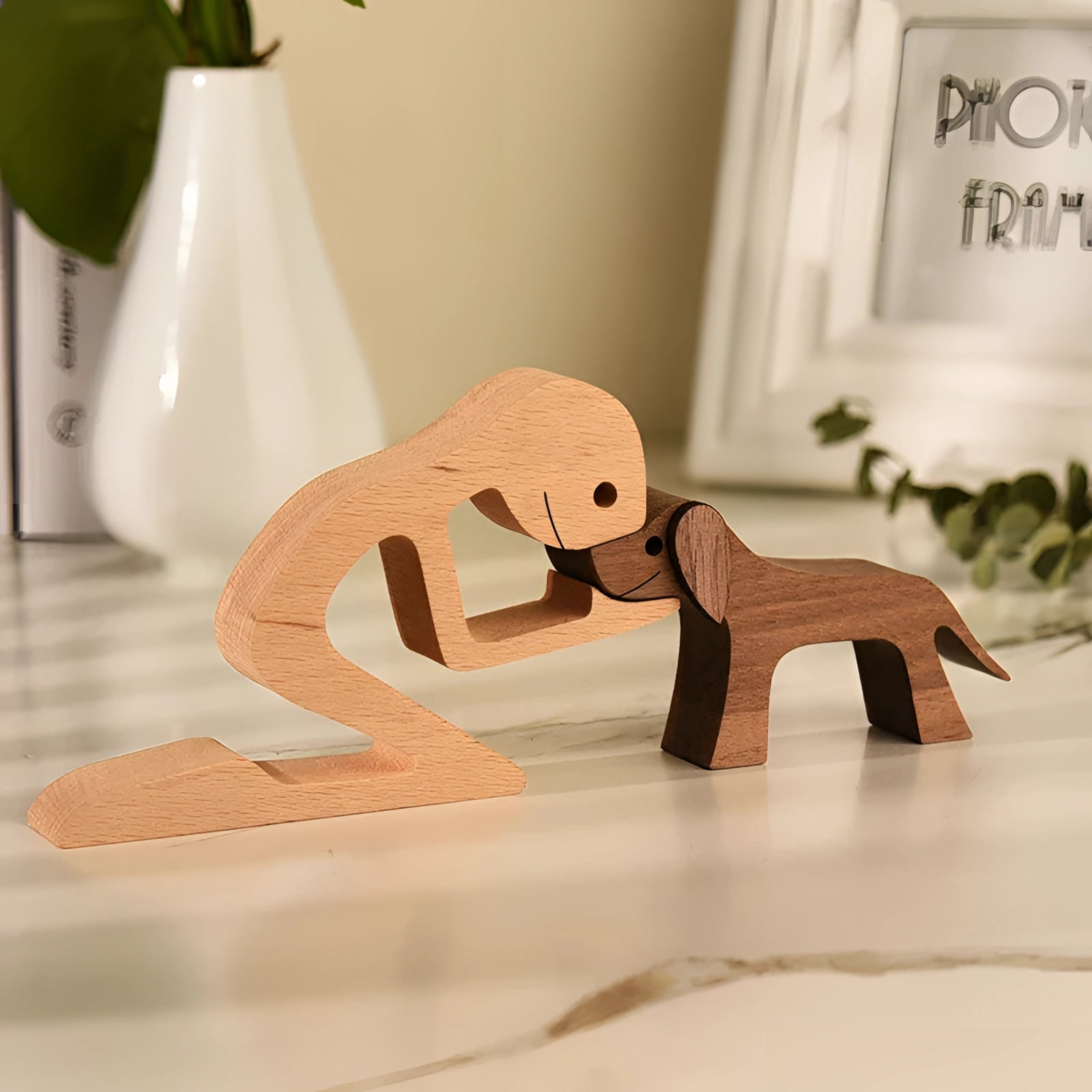 Wooden dog sculpture wearing a striped scarf, resembling a festive holiday figurine, displayed next to a houseplant and a small flowerpot, showcasing hardwood craftsmanship and creative art design.