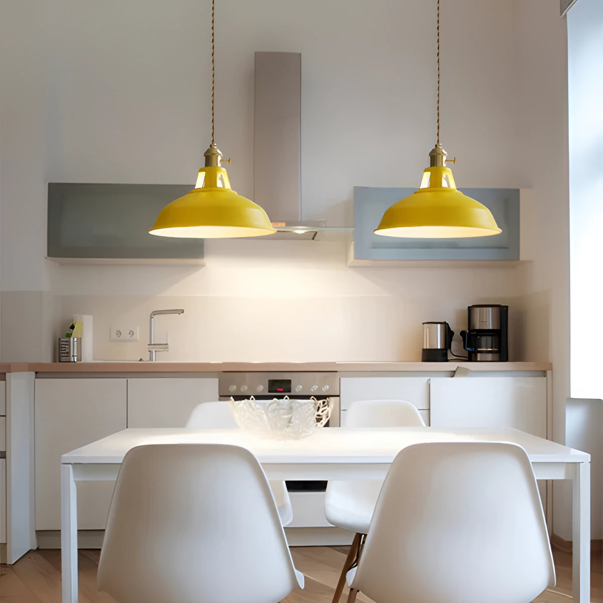 Yellow industrial pendant light hanging in a modern kitchen setting with grey elements, illuminating a dining area with sleek furniture and contemporary interior design.