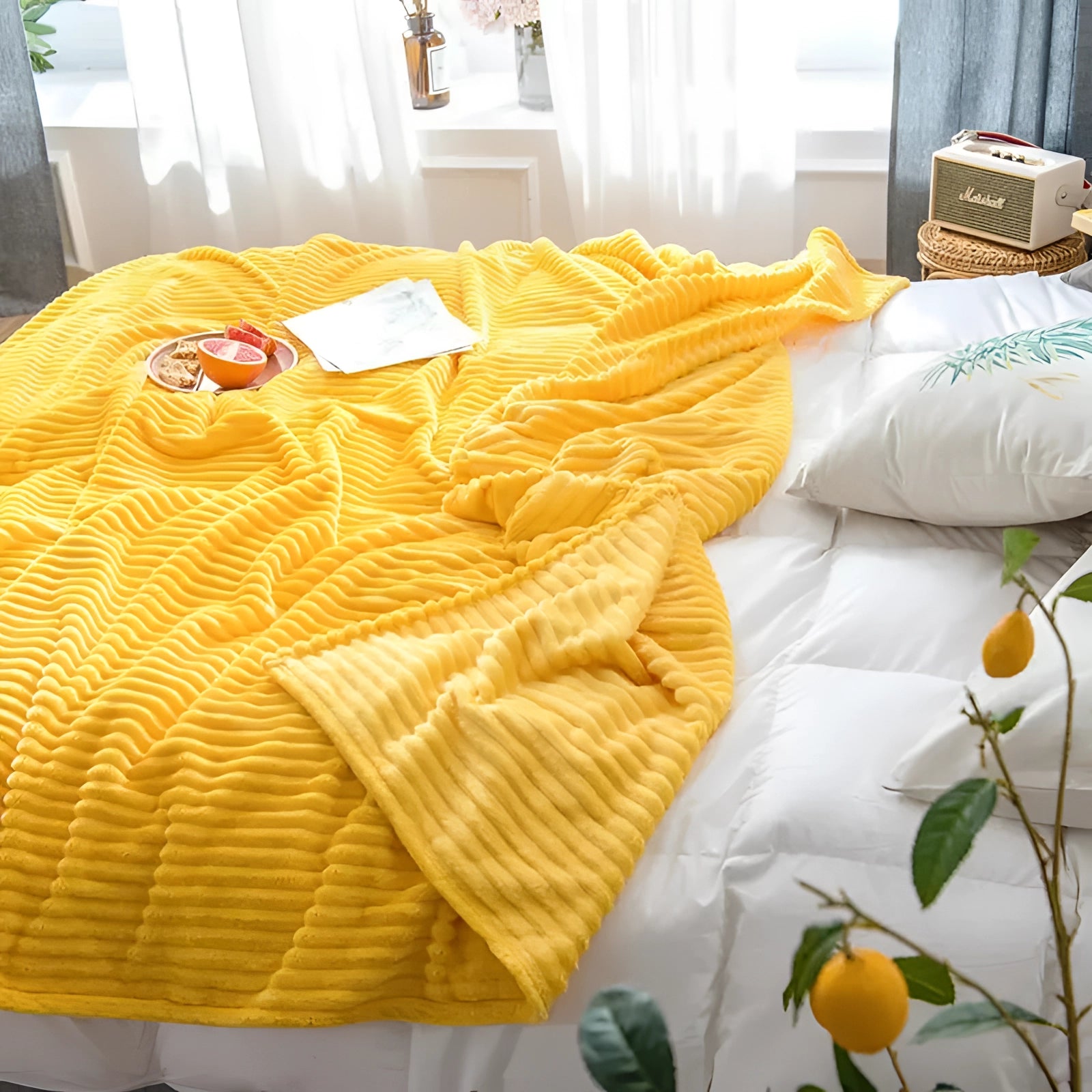 Yellow ribbed blanket draped over a wooden chair in a modern bedroom setting, with a potted plant nearby and warm lighting accentuating the cozy texture.