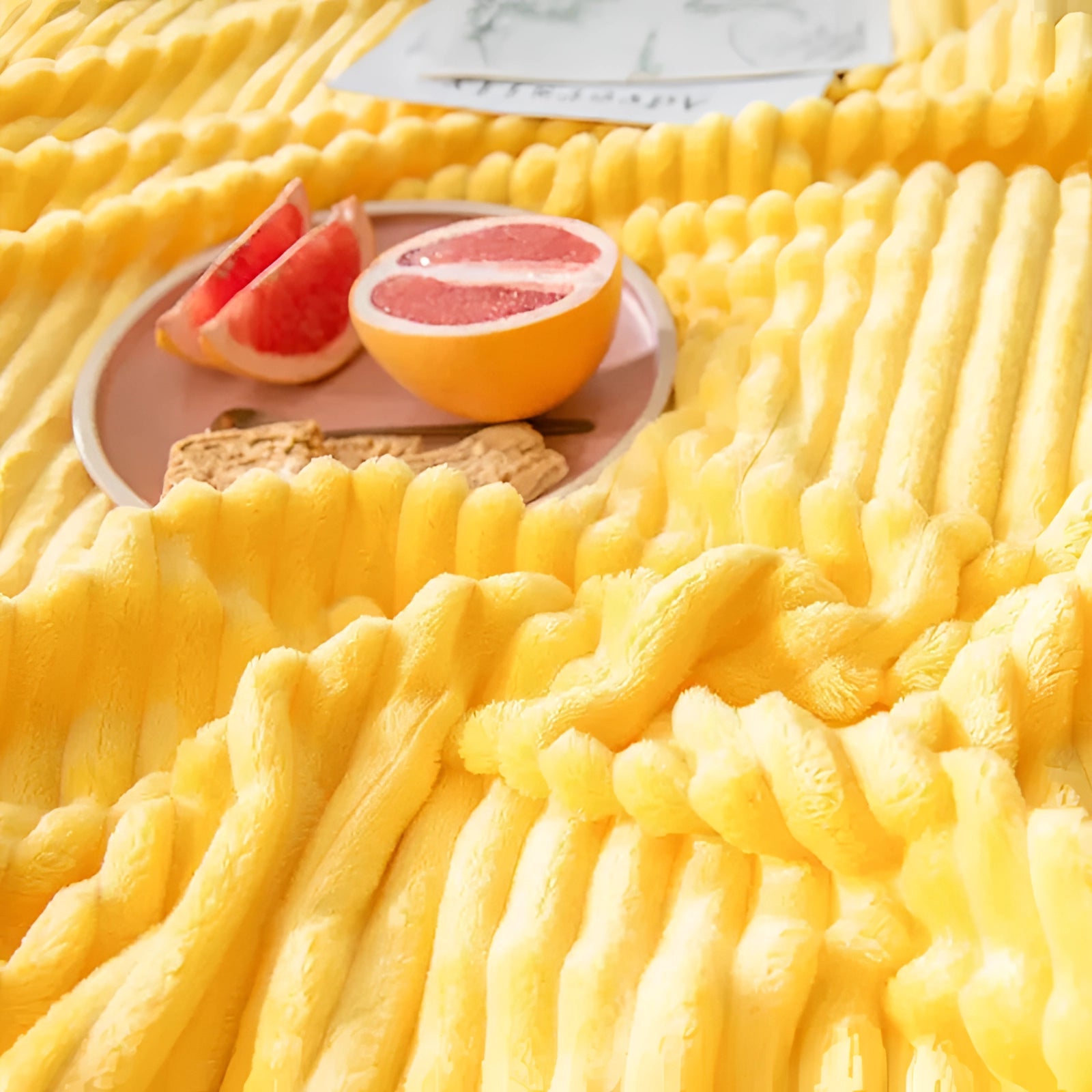 A soft yellow ribbed blanket draped over a couch in a modern bedroom setting.